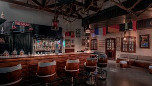 A bar area with wooden stools, a bar counter, and a variety of bottles. - JAZ Fayrouz (Sharm El Sheikh)