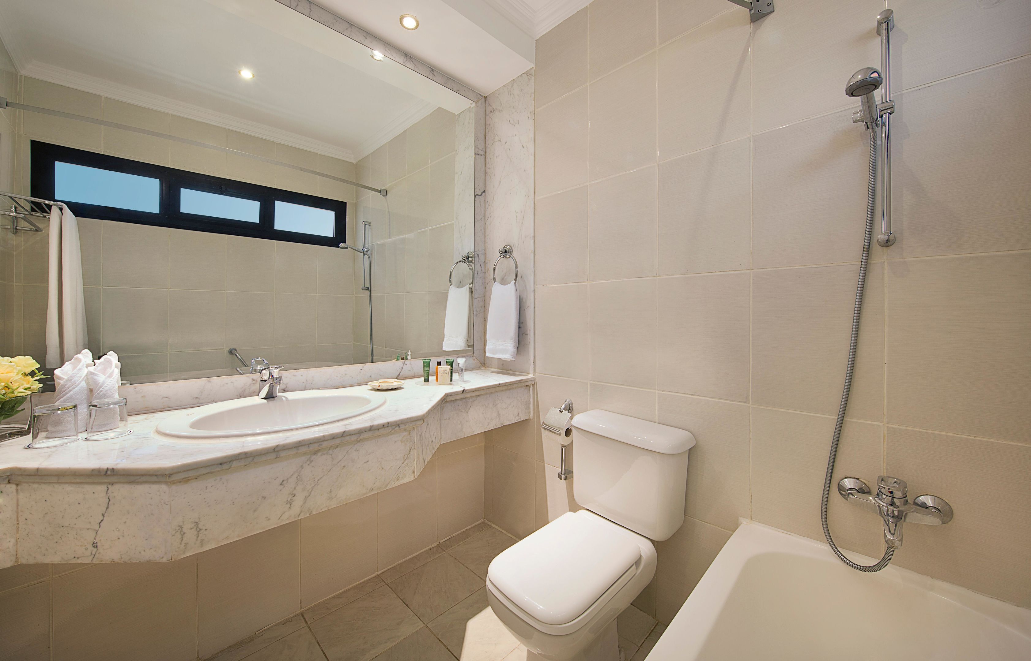 A bathroom with a double sink, a toilet, a bathtub, and a shower.