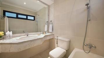A bathroom with a double sink, a toilet, a bathtub, and a shower.
