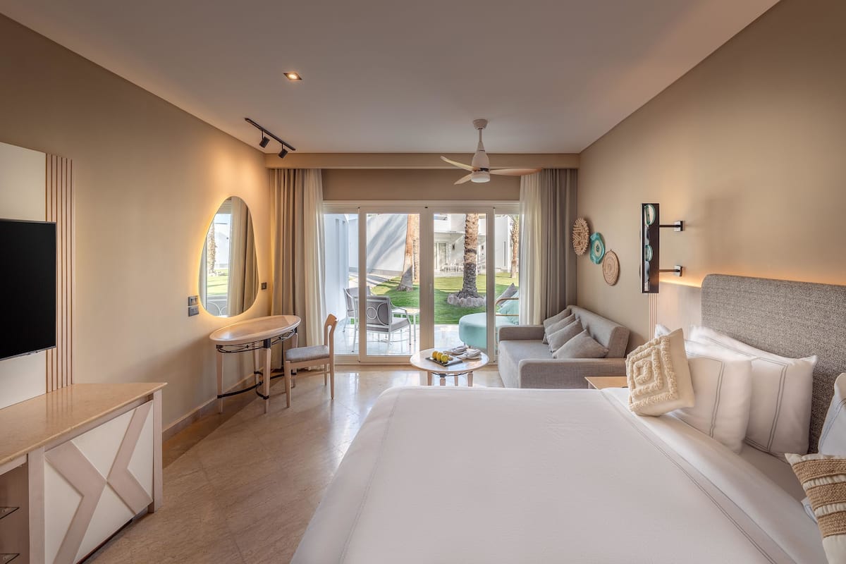 A hotel room with a bed, a desk, a chair, a sofa, and a television.