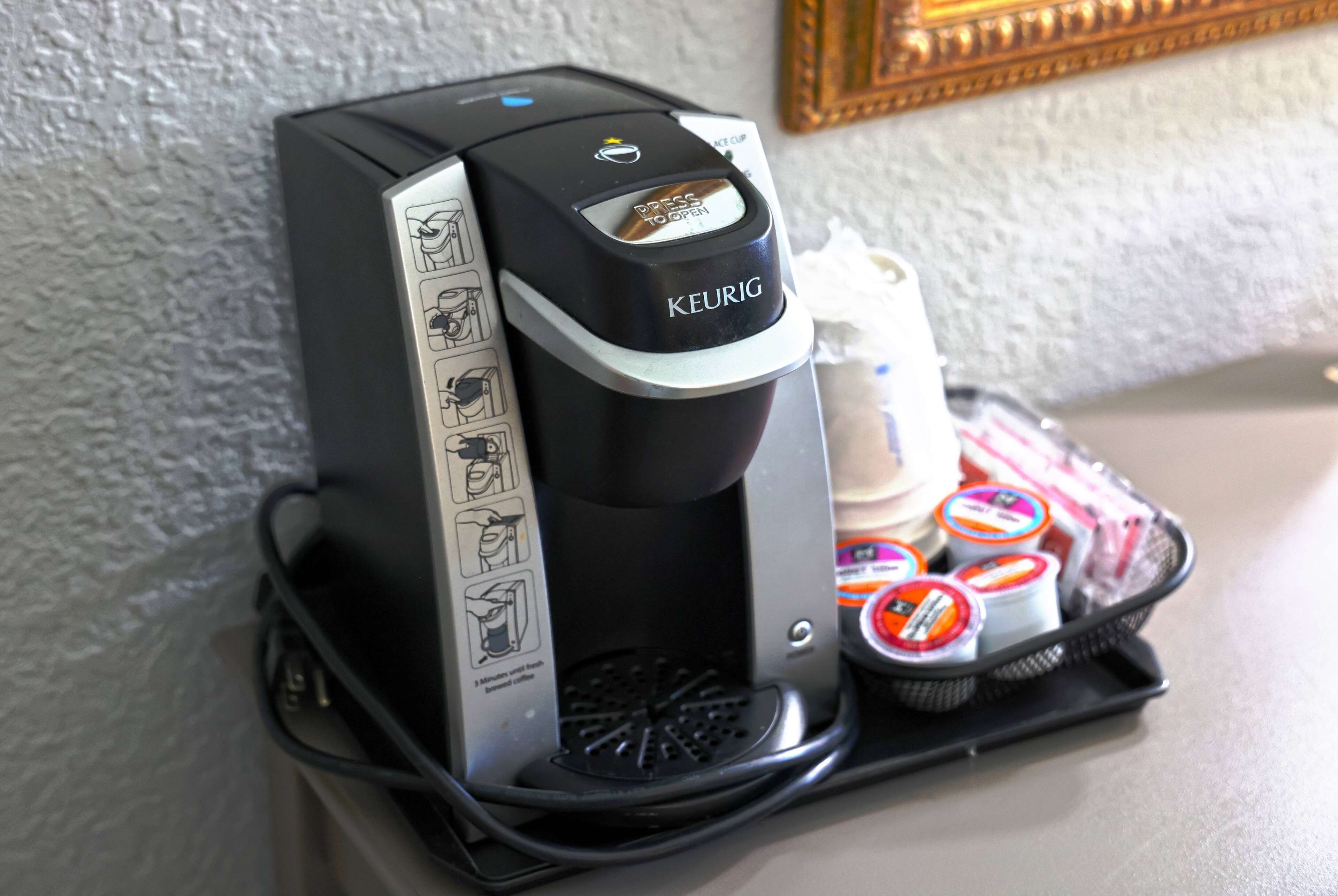 A Keurig coffee maker with a drip tray and a basket of coffee pods.