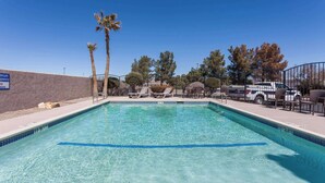 A rectangular pool with clear blue water, surrounded by lounge chairs and palm trees. - Baymont by Wyndham Barstow Historic Route 66 (Barstow)