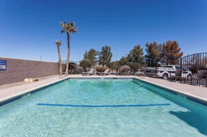 Una piscina al aire libre, sillones reclinables de piscina