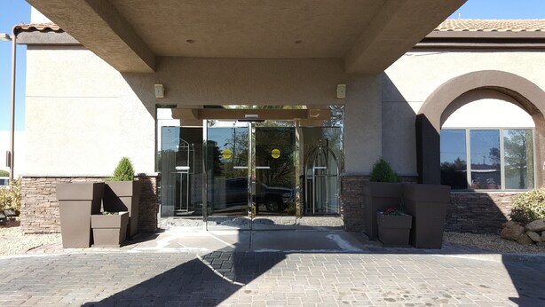 A building entrance with a glass door, a "No Soliciting" sign, and a "Caution" sign. - Baymont by Wyndham Barstow Historic Route 66 (Barstow)