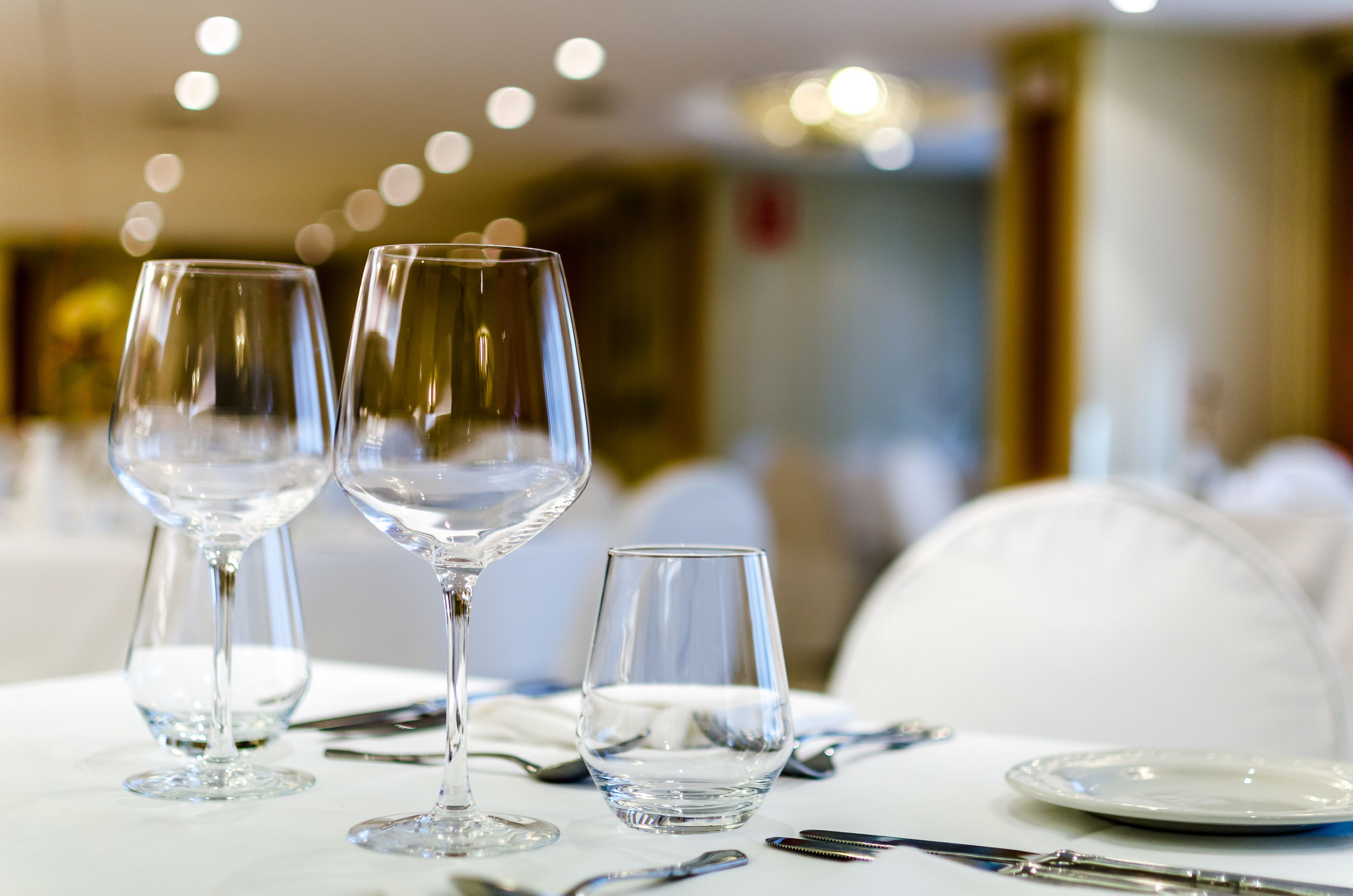 A table set with three wine glasses and a small glass, accompanied by a plate and cutlery.