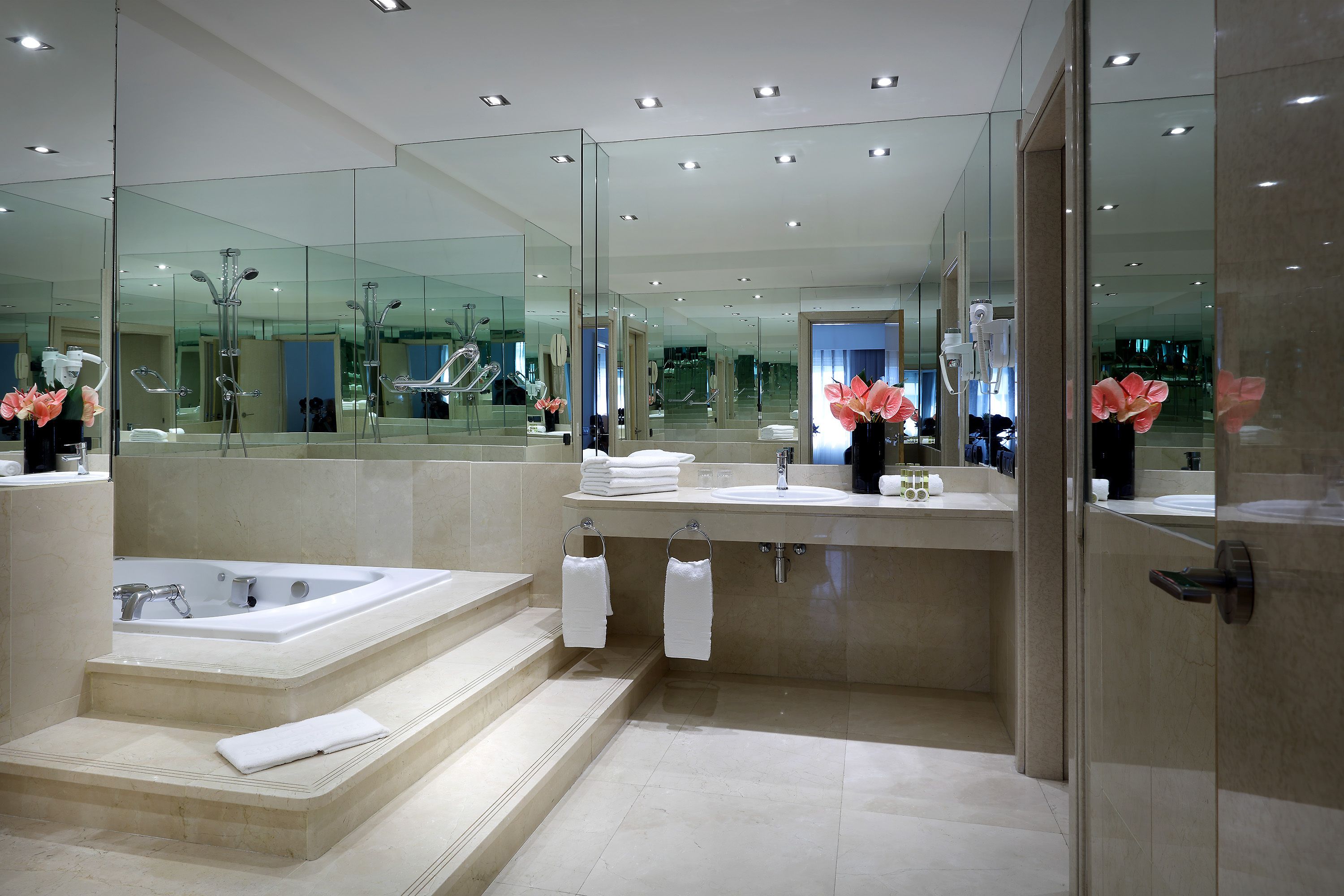 A modern bathroom with a large mirror, a bathtub, and a vanity with a sink.