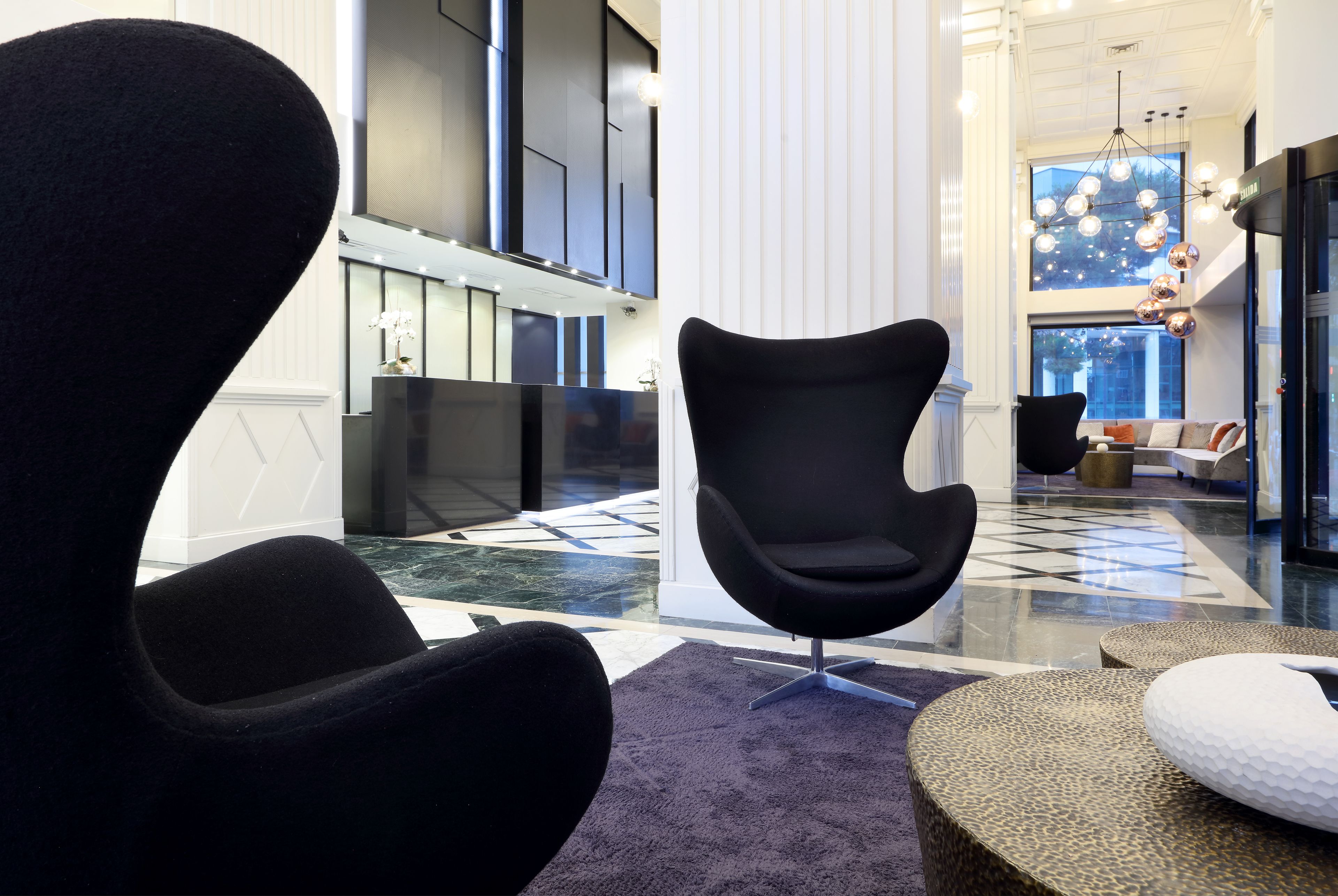 Eine moderne Lobby mit einem schwarzen Sessel, einer Rezeption und einem großen Fenster mit Blick.