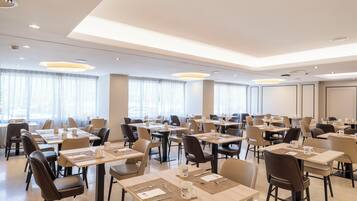 A hotel dining area with multiple tables and chairs, arranged in rows.