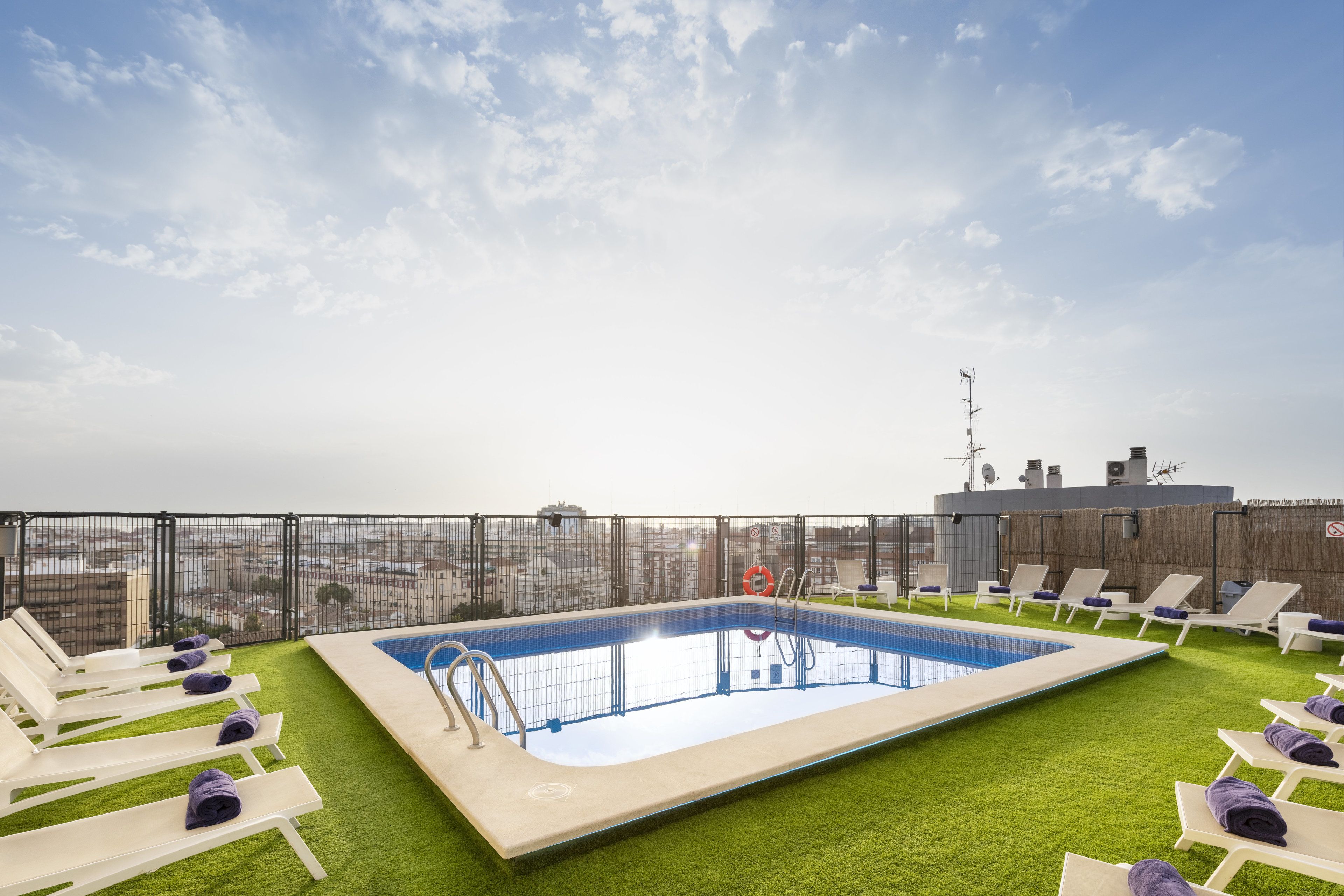 Una piscina al aire libre, sombrillas, sillones reclinables de piscina