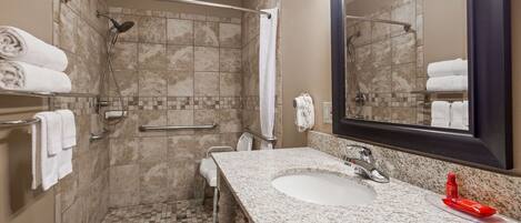 A bathroom with a shower, a sink, and a mirror.
