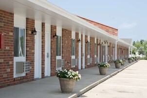 A row of motel rooms with a brick facade, white doors, and air conditioning units.