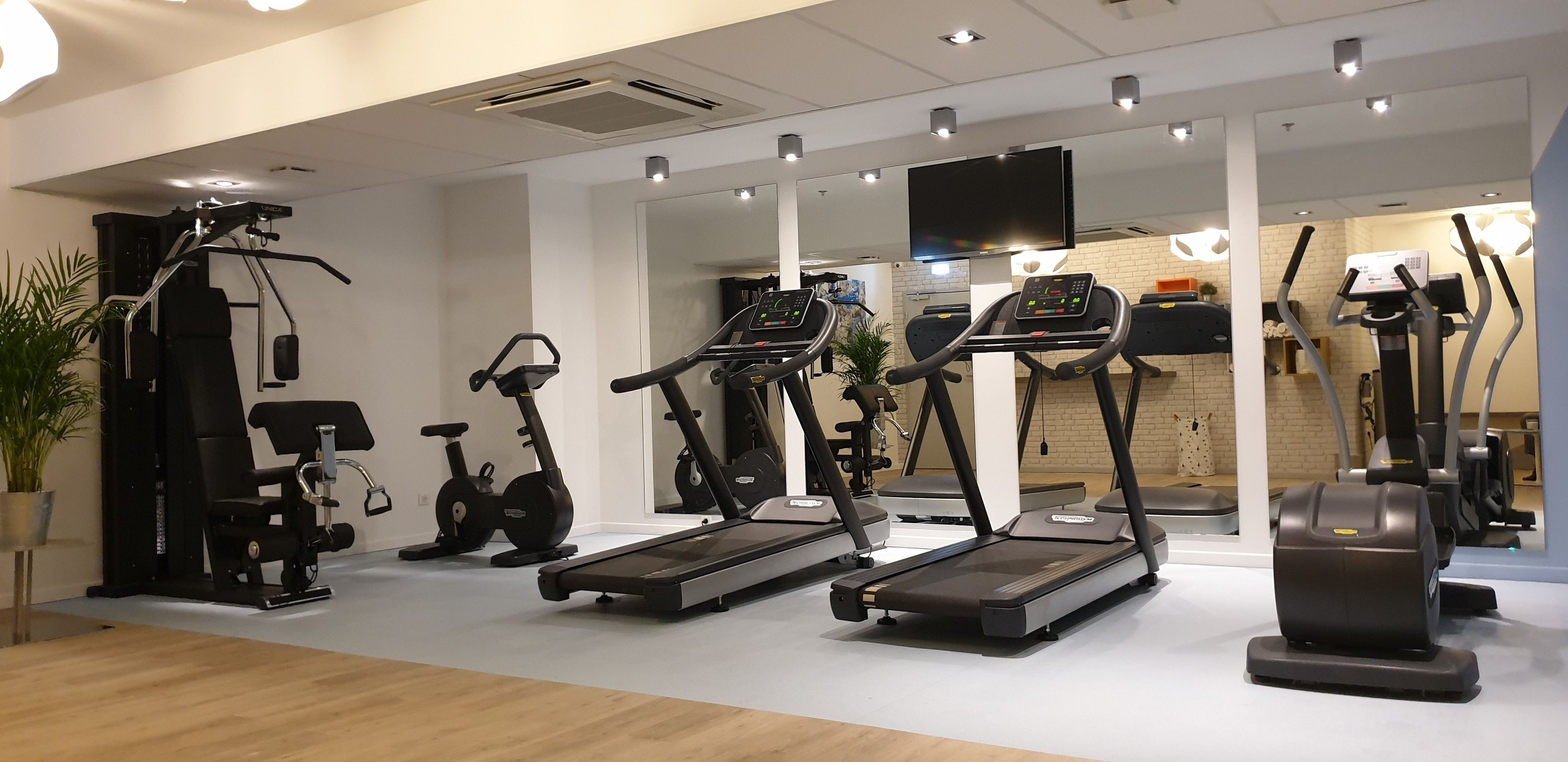Un gimnasio con equipos de ejercicio variados, incluyendo cintas de correr, bicicletas estáticas y máquinas de pesas.