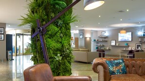 A lobby with leather sofas, a green wall, and a mounted lamp.