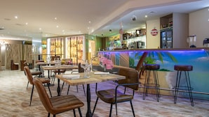 Un restaurante con zona de bar, mesas de madera y taburetes.