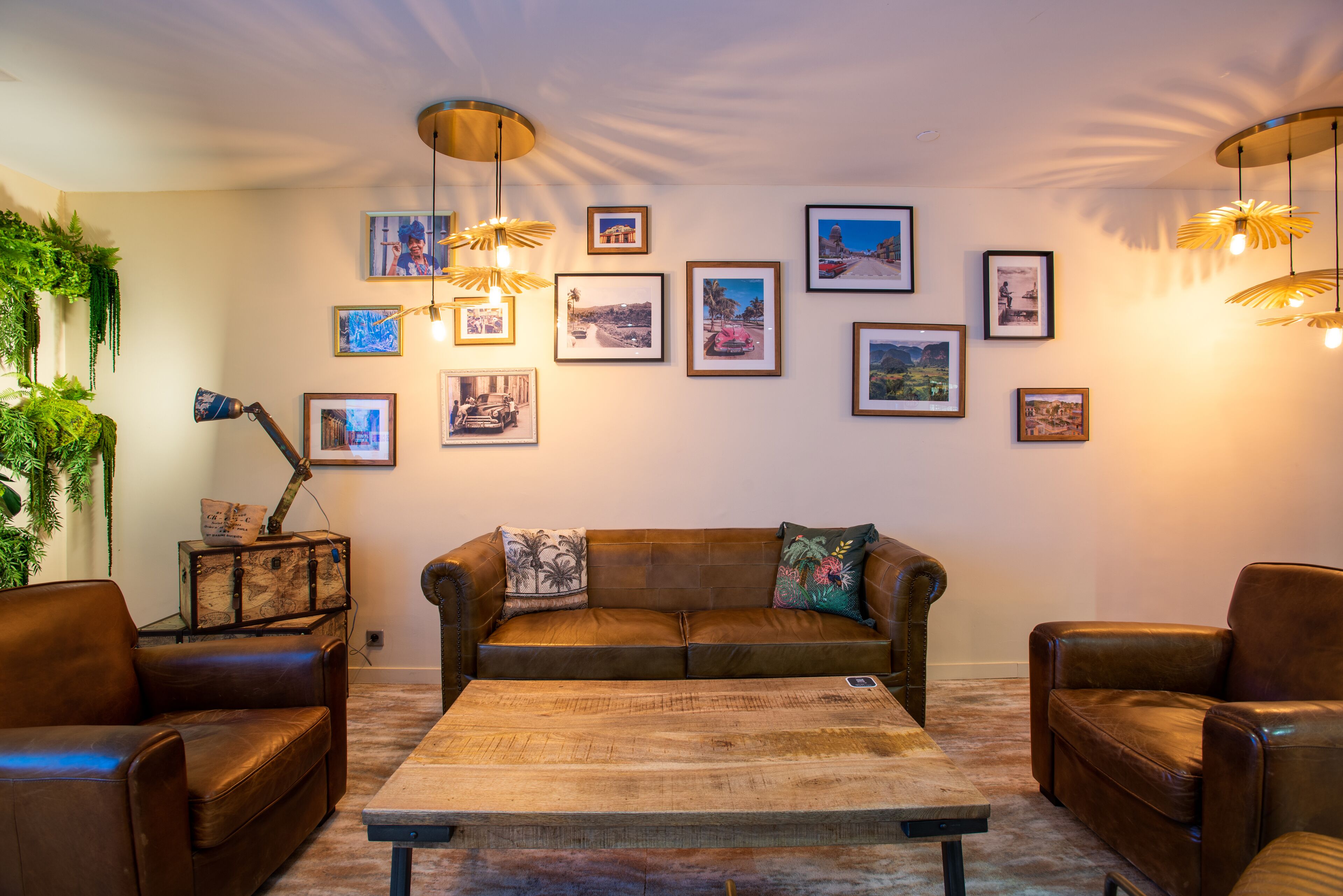 Ein Wohnzimmer mit einem braunen Ledersofa, zwei Sesseln, einem Couchtisch und einer Wand mit gerahmten Bildern.