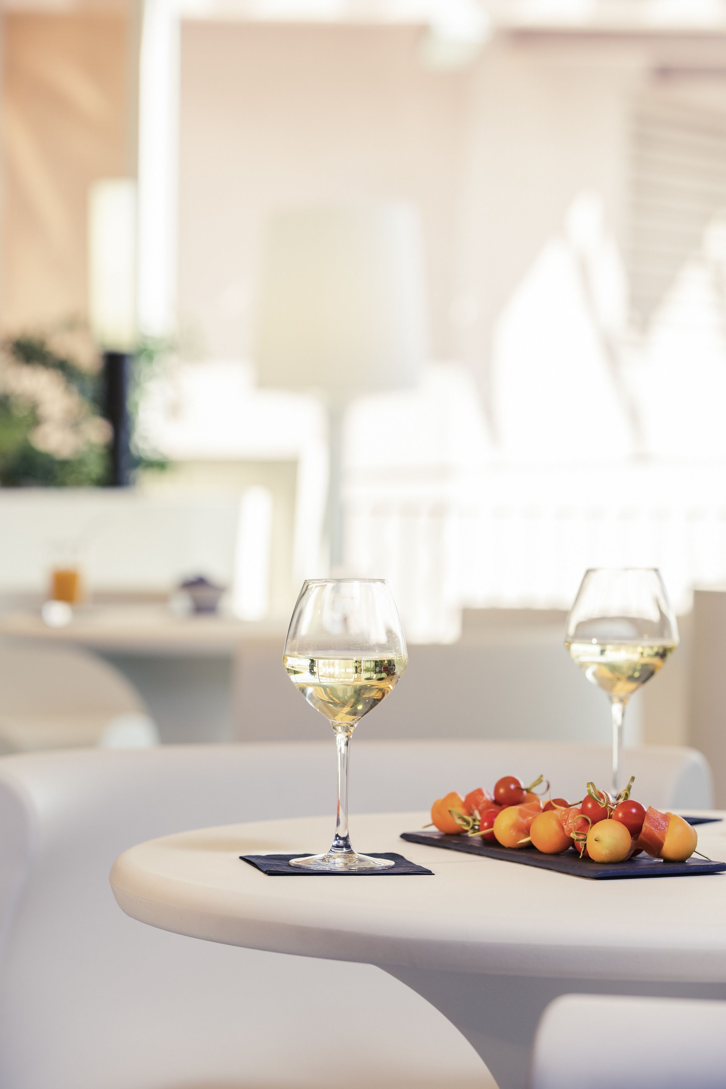 Une table avec deux verres à vin et une assiette de fruits.