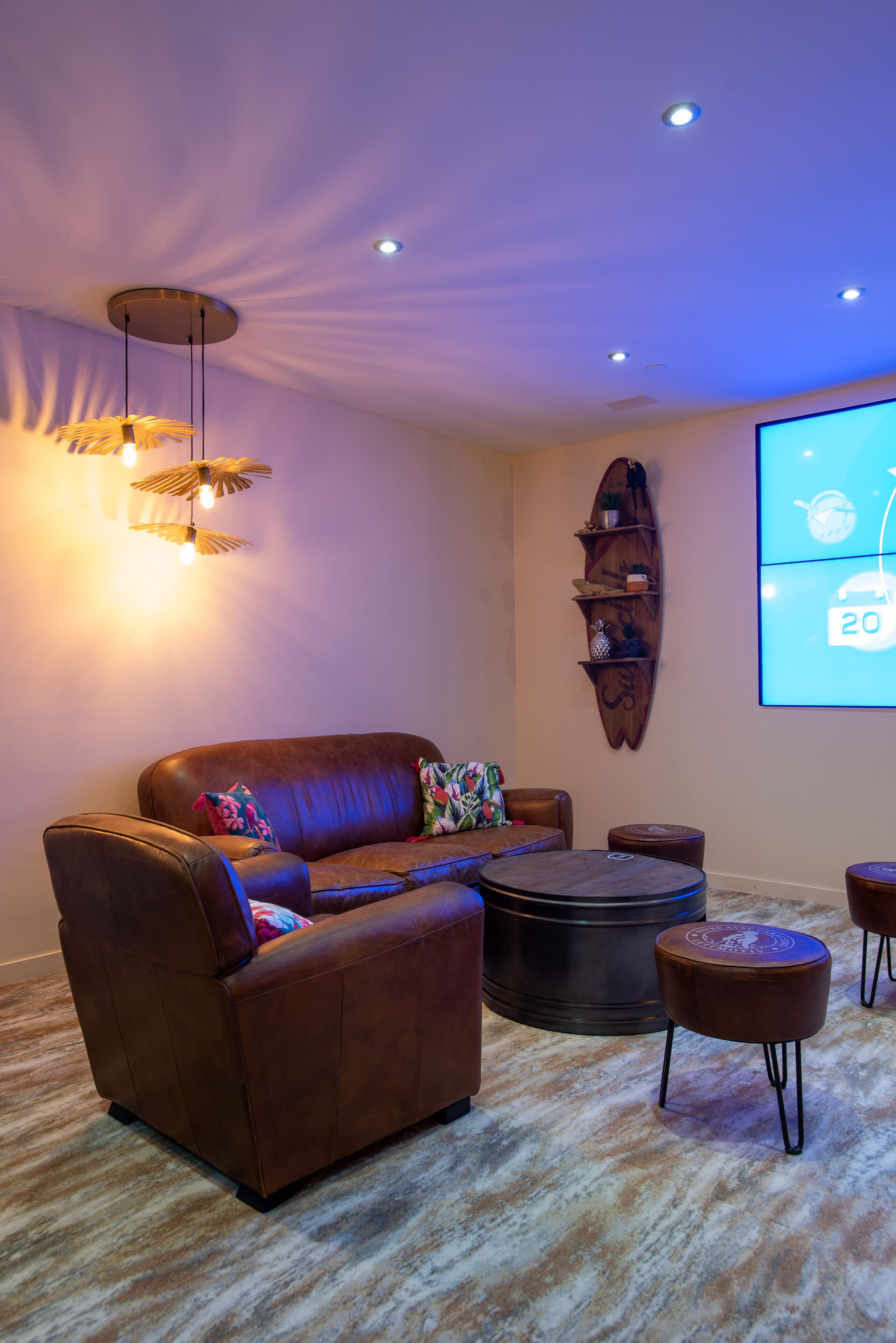 A modern living room with a brown leather sofa, a round coffee table, and a projector screen displaying a calendar.