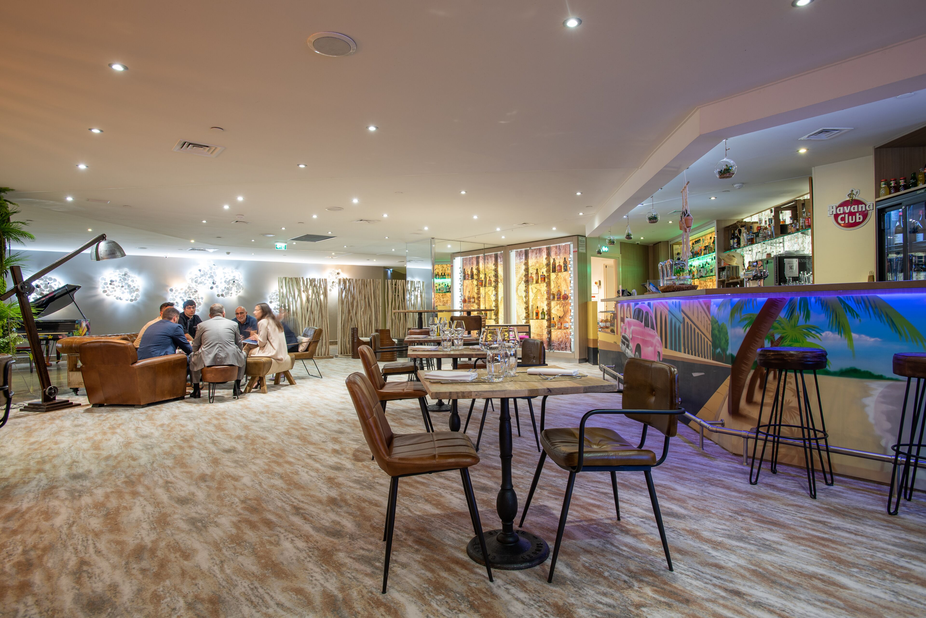Un área de bar moderna con mostrador, asientos y un mural.
