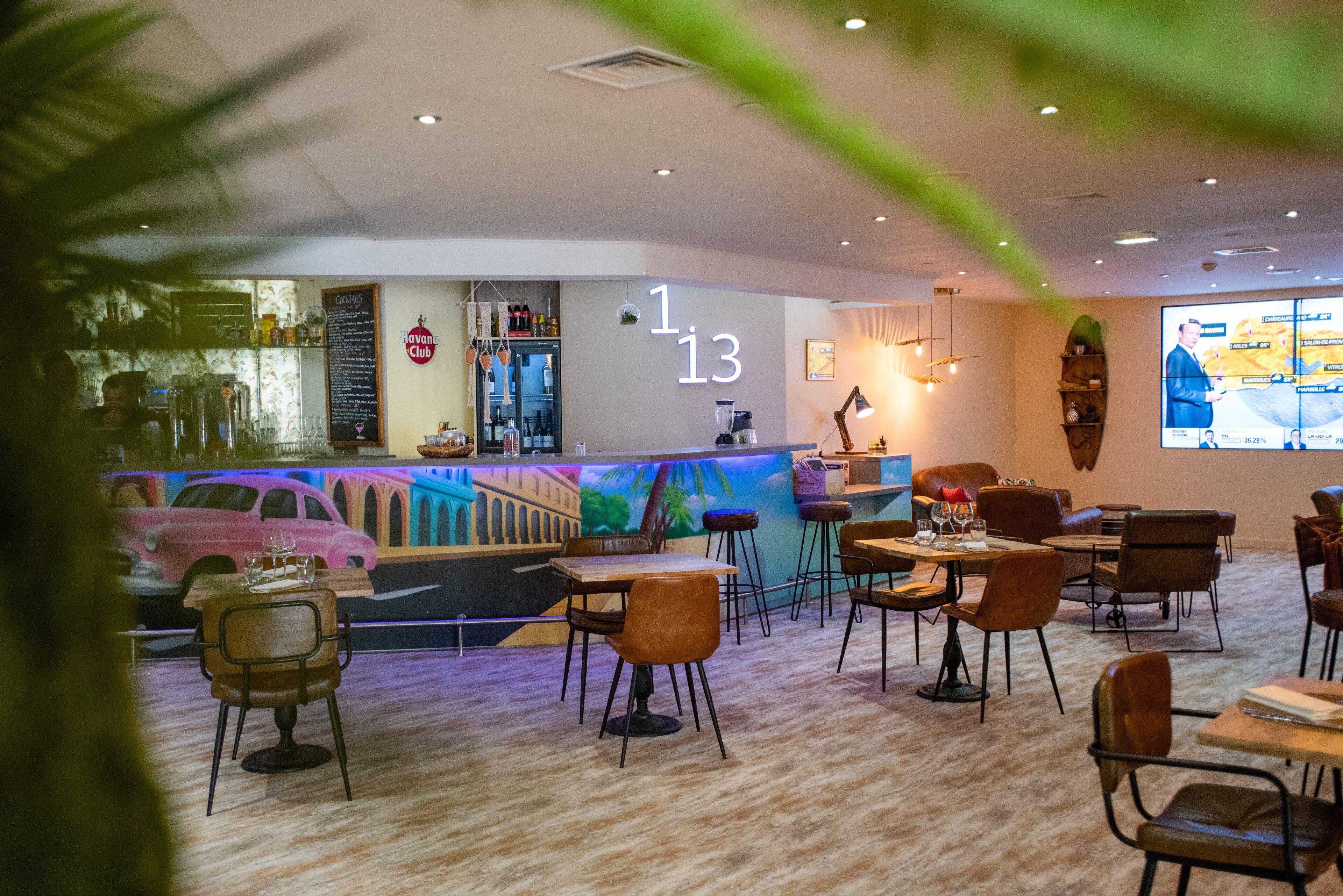 A restaurant with a bar area, wooden tables, and chairs.