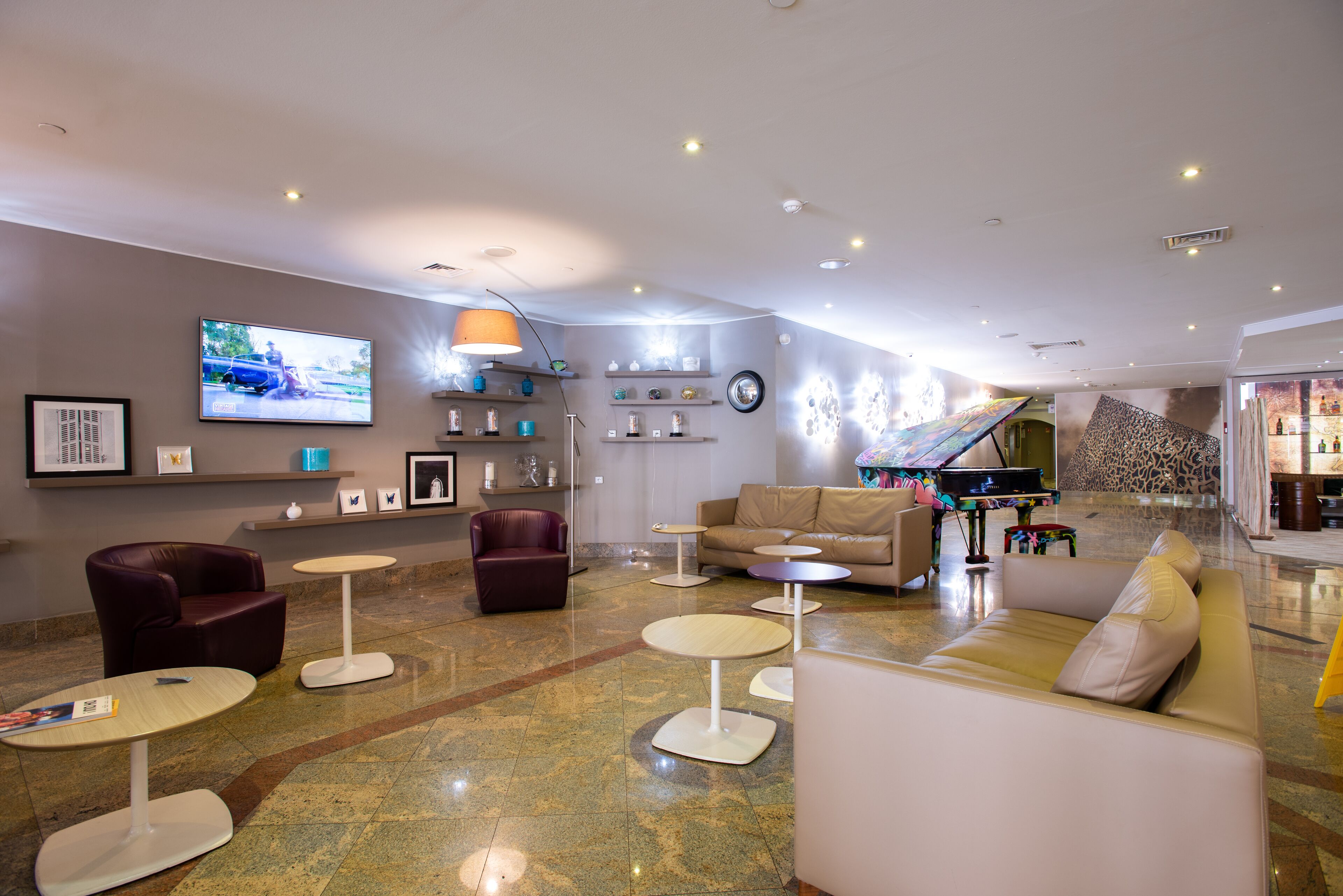 Eine moderne Lobby mit Sitzbereichen, einem Fernseher und einem Klavier.