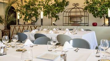 Un restaurante con mesas dispuestas para comer, rodeado de follaje y detalles decorativos.
