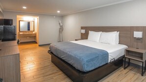 Una habitación de hotel moderna con una cama, una mesita de noche y un pequeño escritorio con una silla.