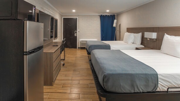 Habitación de hotel con kitchenette, dos camas, un escritorio y un baño.