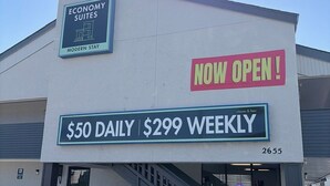 Un edificio con un letrero que indica 'Economy Suites' y 'Modern Stay', con opciones de precios de '$50 Diario' y '$299 Semanal'.