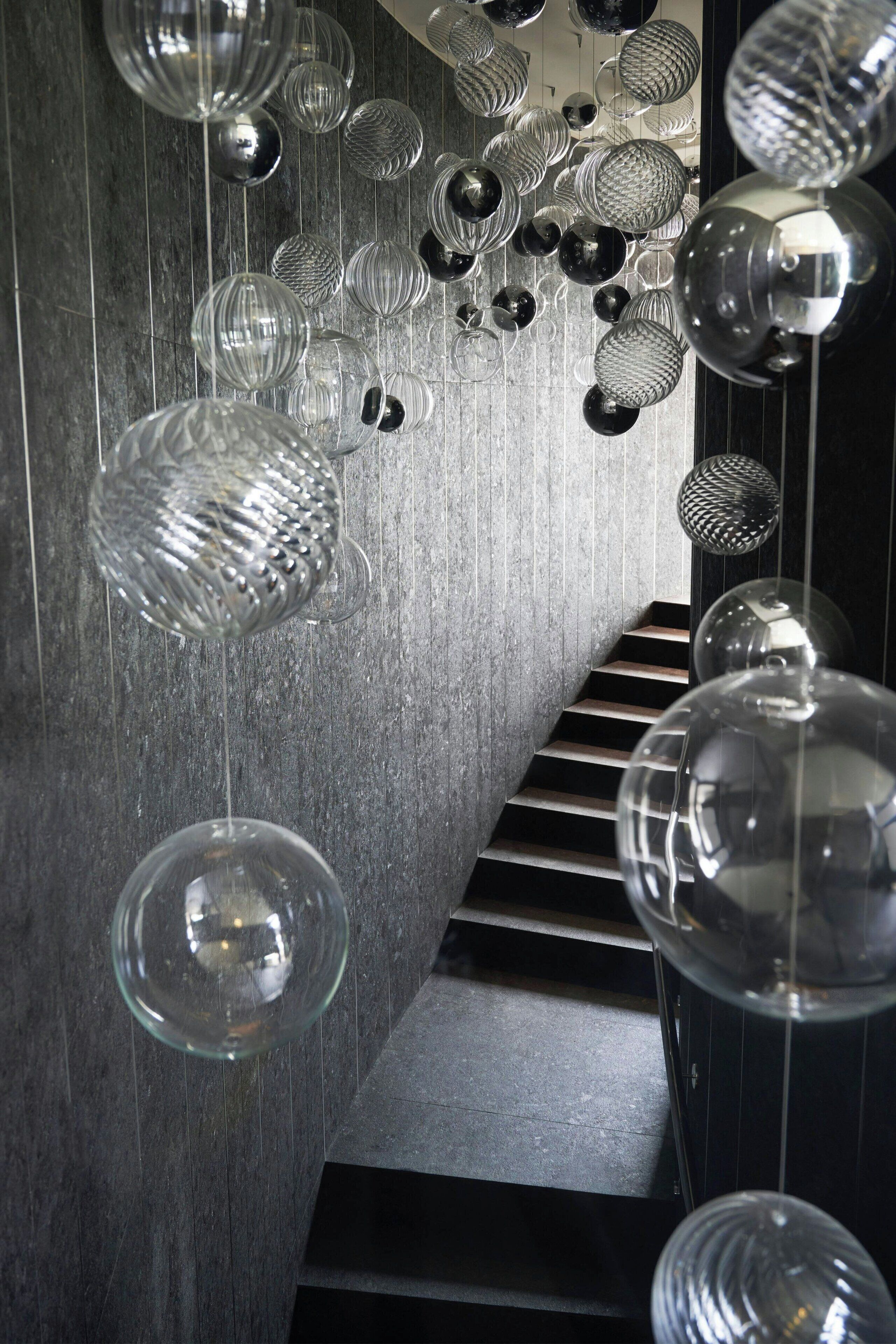 A staircase with a modern design, featuring a series of hanging spherical light fixtures.