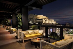 A rooftop terrace with wicker furniture, a yellow sofa, and a view of a historic building at night. - Excelsior Hotel Gallia, a Luxury Collection Hotel, Milan (Milan)