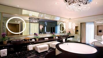 A modern bathroom with a large mirror, round lights, a bathtub, and a vanity with a sink.