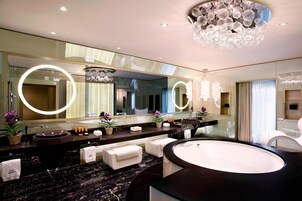 A modern bathroom with a large mirror, round lights, a bathtub, and a vanity with a sink.