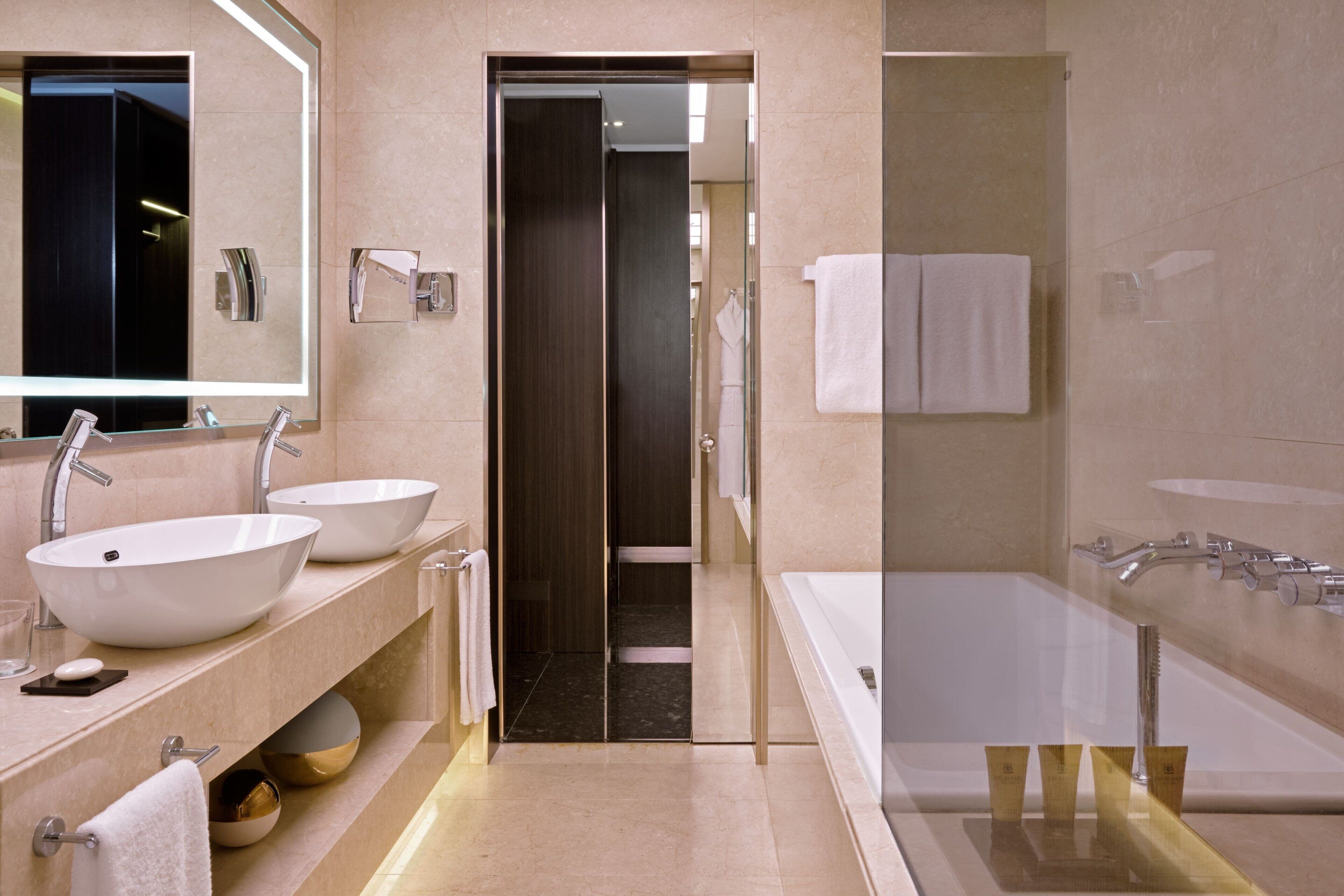 Un bagno moderno con due lavandini, una vasca da bagno ampia e uno specchio.