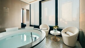 A modern bathroom with a large bathtub, two white chairs, and a small table with a vase. - Excelsior Hotel Gallia, a Luxury Collection Hotel, Milan (Milan)