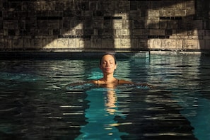 A person swimming in a pool with a stone wall in the background. - Excelsior Hotel Gallia, a Luxury Collection Hotel, Milan (Milan)