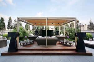 Een overdekt terras met een bank, twee tafels en een televisie.