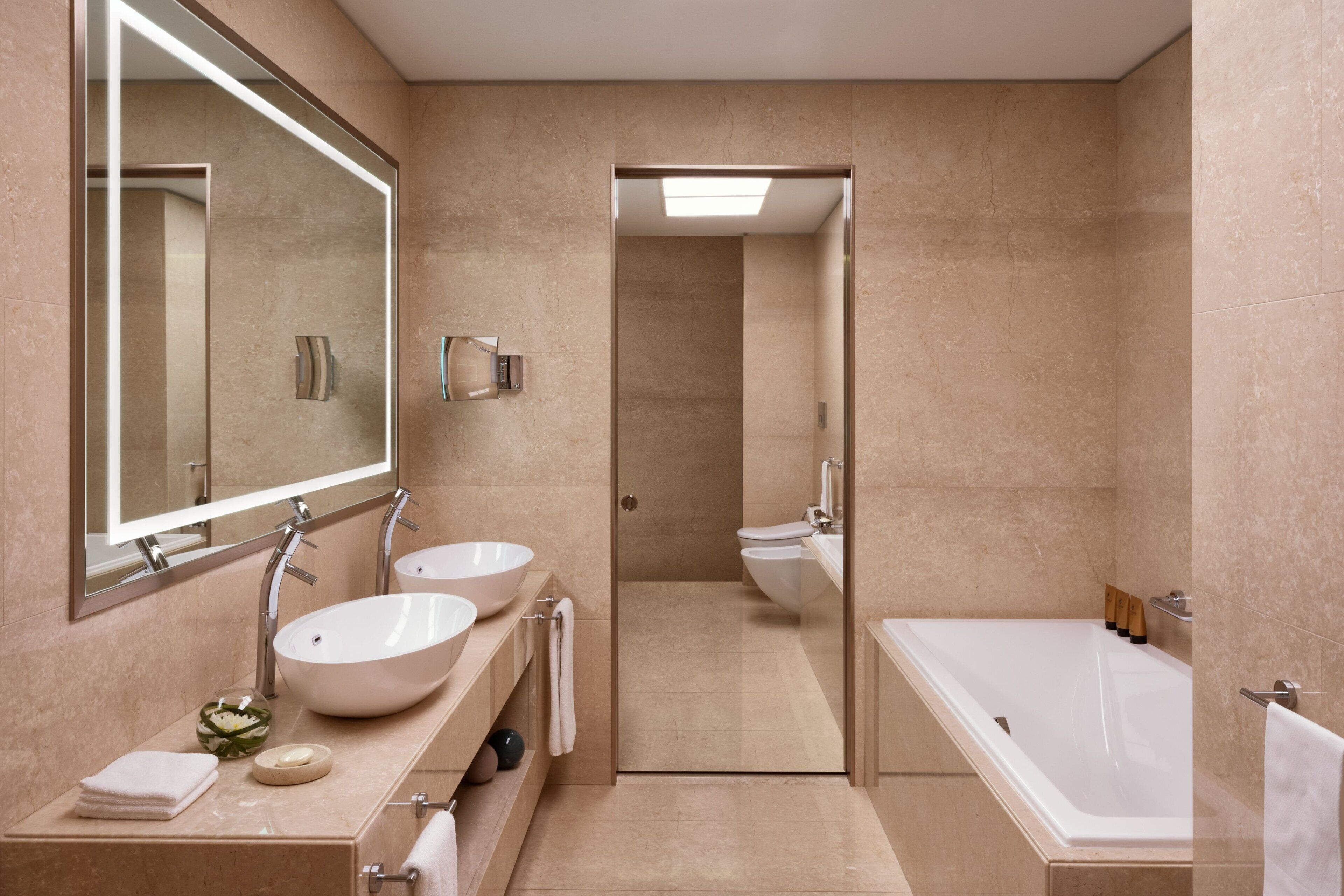 Un bagno moderno con due lavandini, uno specchio grande, una vasca da bagno e uno spazio doccia.