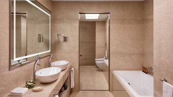 Un bagno moderno con due lavandini, uno specchio grande, una vasca da bagno e uno spazio doccia.