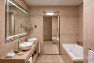 Un bagno moderno con due lavandini, uno specchio grande, una vasca da bagno e uno spazio doccia.