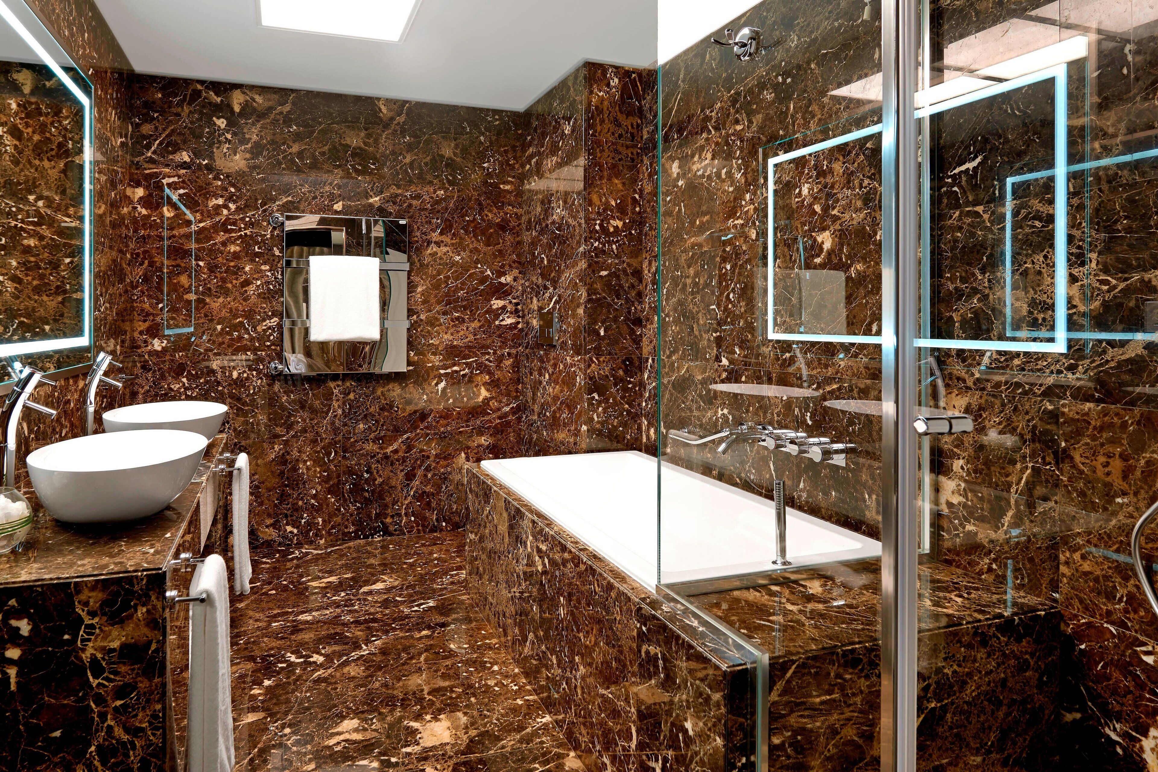 Een moderne badkamer met een marmeren vloer, een vrijstaand bad en een douchecabine met glazen wanden.