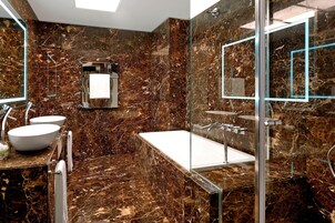 Een moderne badkamer met een marmeren vloer, een vrijstaand bad en een douchecabine met glazen wanden.