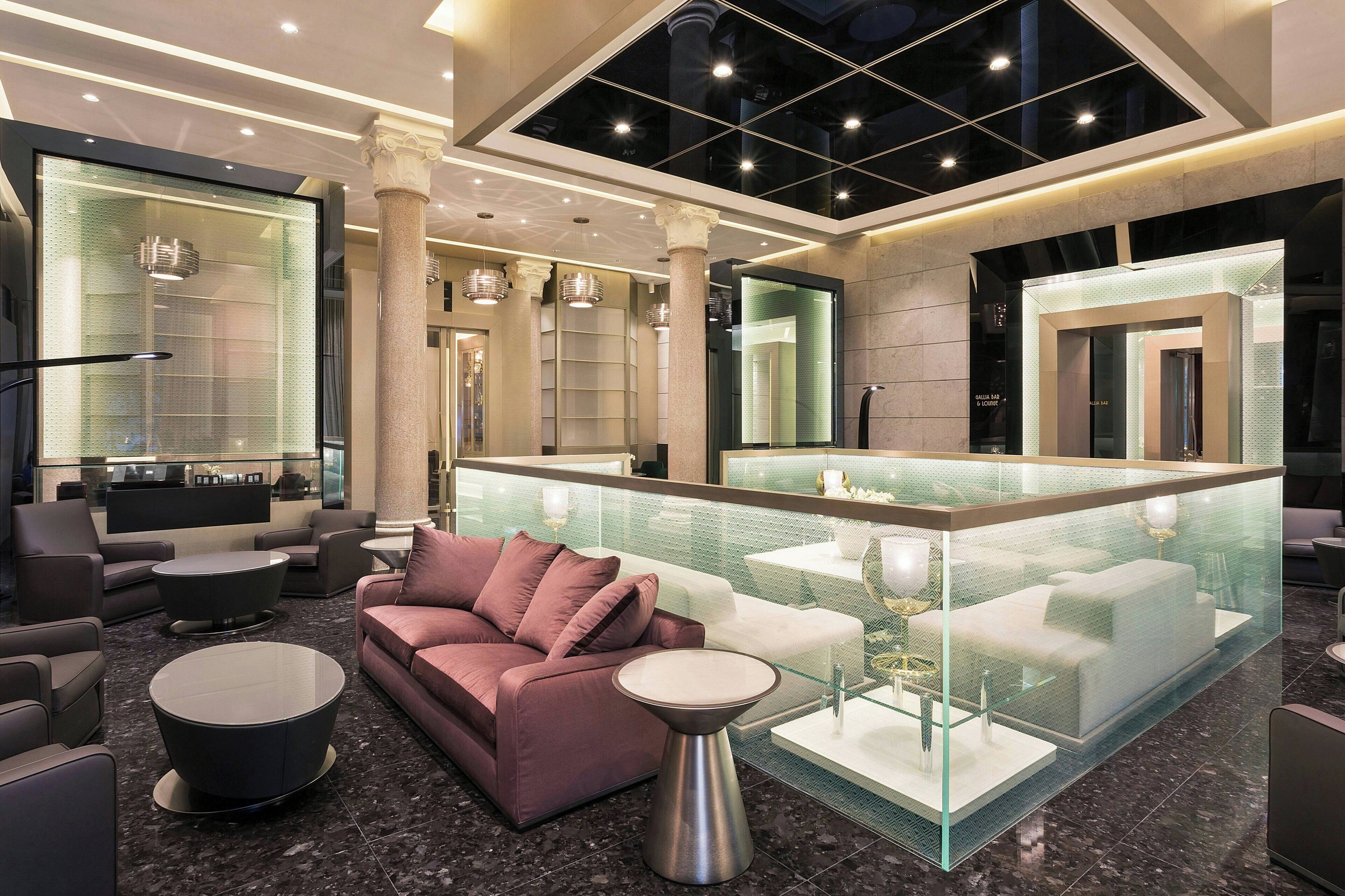 A modern lobby with a seating area, a glass partition, and a reception desk.