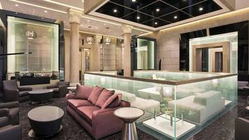 A modern lobby with a seating area, a glass partition, and a reception desk.