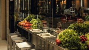 A modern kitchen with stainless steel appliances, a glass counter displaying fresh produce, and bar stools. - Excelsior Hotel Gallia, a Luxury Collection Hotel, Milan (Milan)
