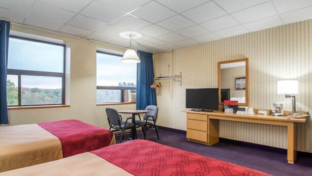 A hotel room with two beds, a desk with a computer, a chair, a TV, and a window with a view. - Econo Lodge Manchester (Manchester)