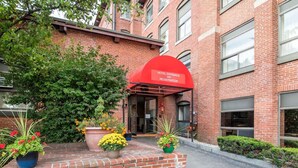 A hotel entrance with a red awning, brick facade, and potted plants. - Econo Lodge Manchester (Manchester)
