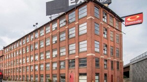 A multi-story brick building with a large sign for 'EXIT 4' and a smaller sign for 'EconoLodge'. - Econo Lodge Manchester (Manchester)