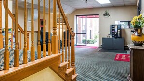 A hotel lobby with a wooden staircase, a reception desk, and a vending machine. - Econo Lodge Manchester (Manchester)
