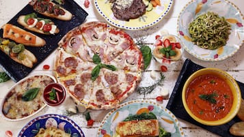 Une variété de plats, notamment des pizzas, des pâtes et un bol de soupe, disposés sur une table.