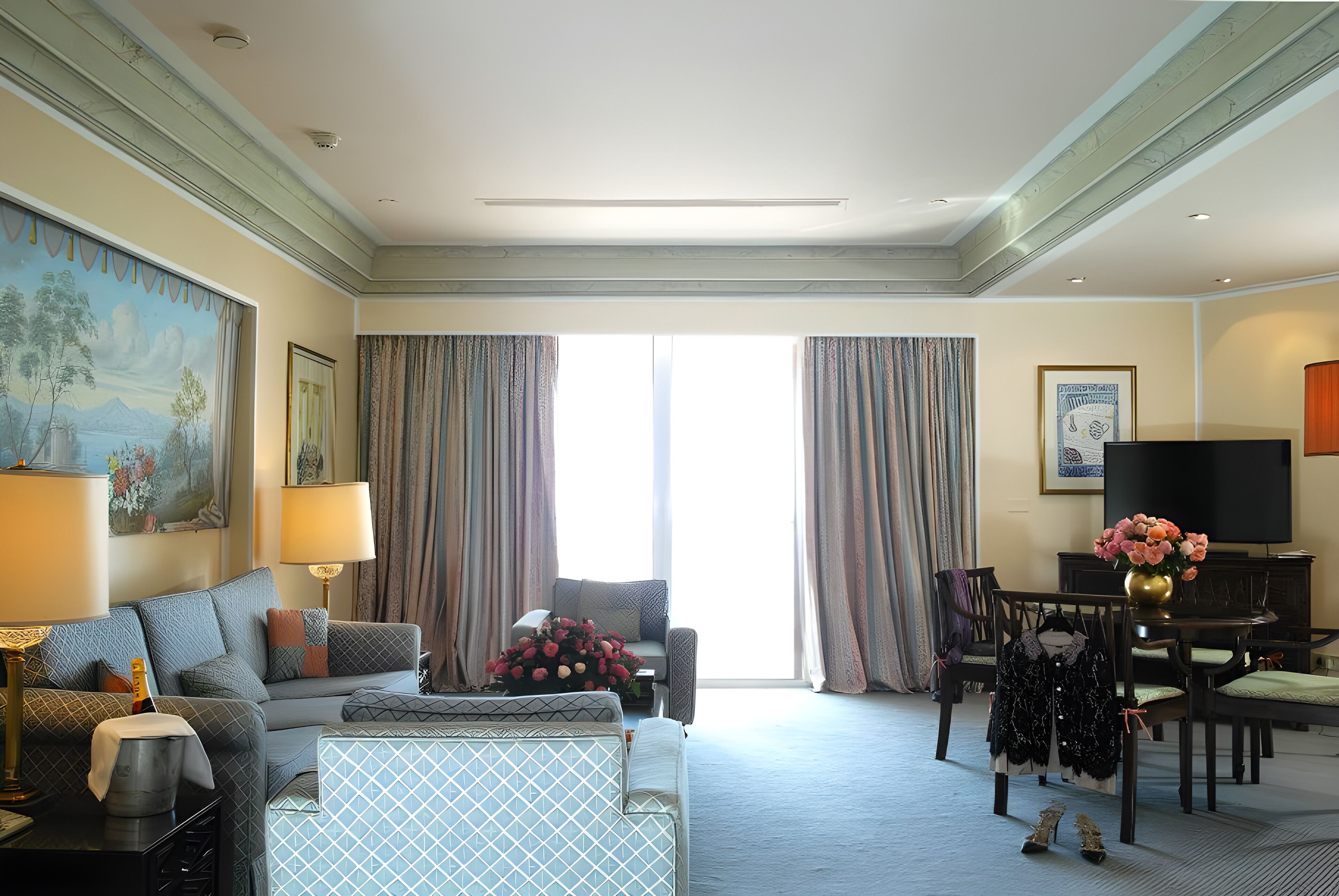Une chambre d’hôtel avec un canapé, des fauteuils, une table à manger, un téléviseur et un tableau au mur.